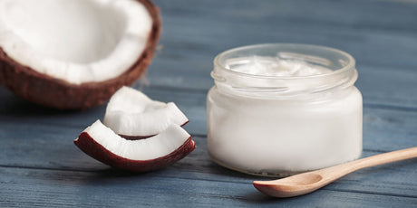 An image of organic coconut oil and coconut fruit on a blue table.