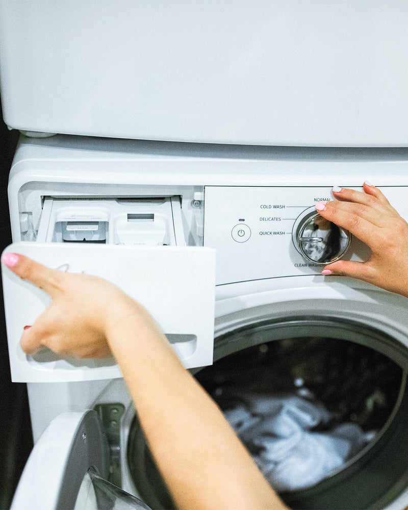 Person interacting with a washing machine, opening the door and adjusting settings.