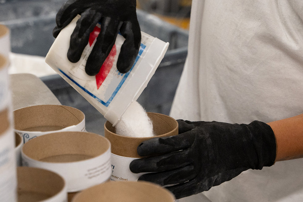 A photo of an employee filling Meliora Laundry Powder canisters at the company's factory in Chicago.