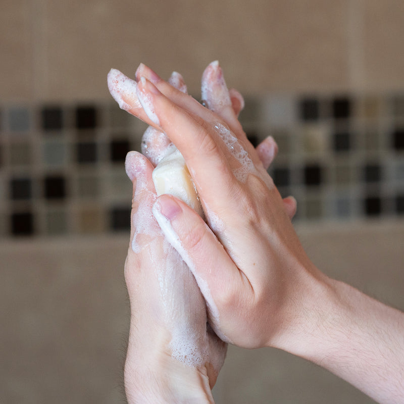 A photo of hands lathering a bar of Meliora soap.